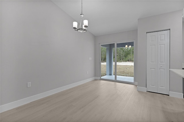 empty room featuring lofted ceiling, a chandelier, and light hardwood / wood-style floors