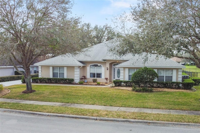 ranch-style home featuring a front yard, roof with shingles, fence, and stucco siding