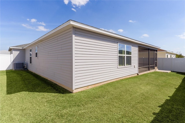 view of side of property with central AC unit, fence, and a yard