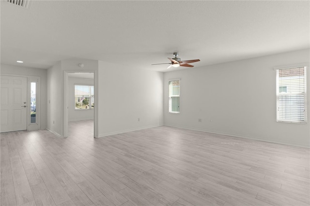 interior space with ceiling fan, light wood-type flooring, plenty of natural light, and baseboards