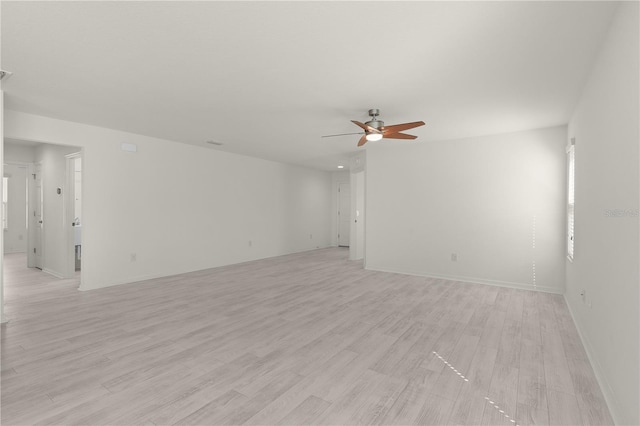 spare room featuring light wood-style floors, ceiling fan, and baseboards