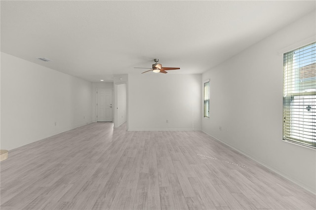 spare room with light wood-style floors, visible vents, baseboards, and a ceiling fan