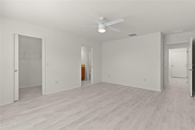 unfurnished bedroom with baseboards, visible vents, light wood-style flooring, a spacious closet, and a closet