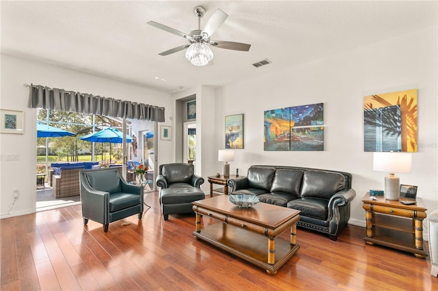 living room with a ceiling fan, baseboards, visible vents, and wood finished floors