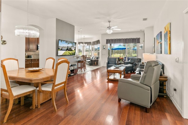 dining space featuring visible vents, wood finished floors, and ceiling fan with notable chandelier