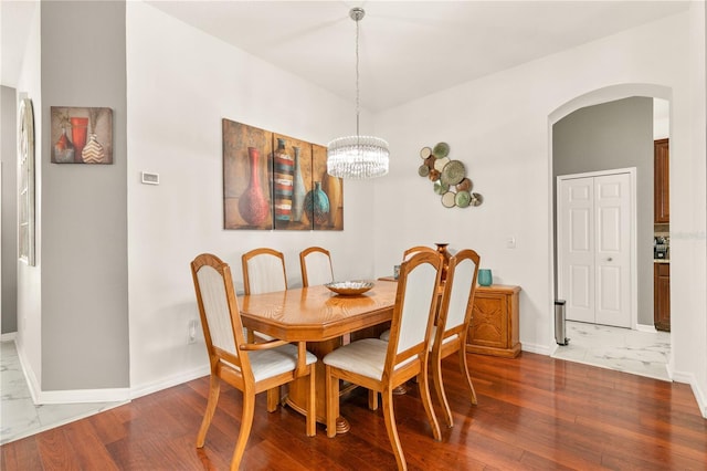 dining room featuring marble finish floor, baseboards, arched walkways, and an inviting chandelier