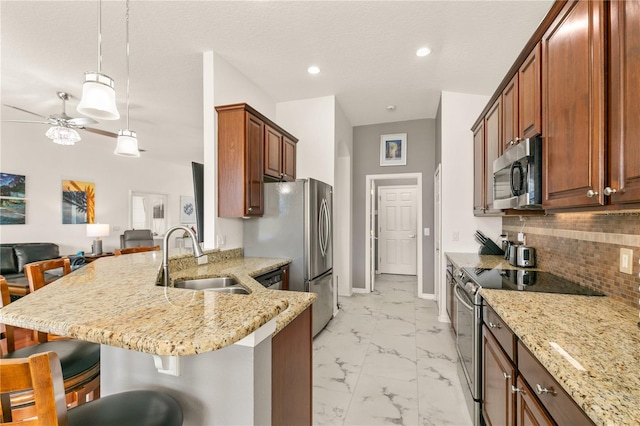 kitchen with light stone counters, a kitchen breakfast bar, marble finish floor, appliances with stainless steel finishes, and pendant lighting