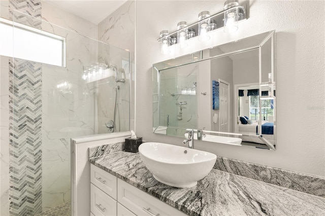 full bathroom featuring a textured wall, a marble finish shower, and vanity