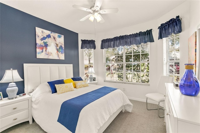 bedroom with light carpet, multiple windows, a ceiling fan, and baseboards