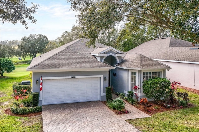 view of front of home featuring an attached garage, a shingled roof, decorative driveway, and stucco siding