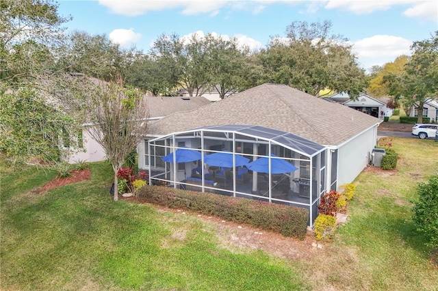 back of property featuring roof with shingles, glass enclosure, a yard, and central AC unit