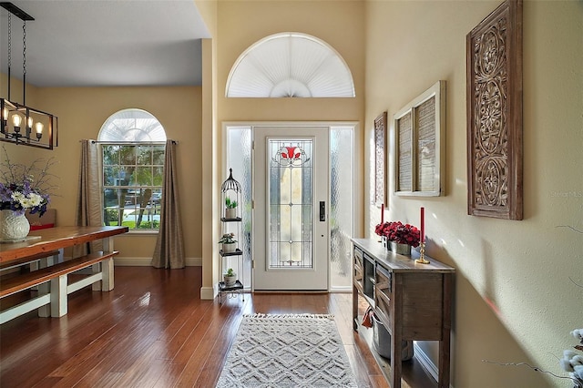 entryway with dark hardwood / wood-style flooring and a notable chandelier