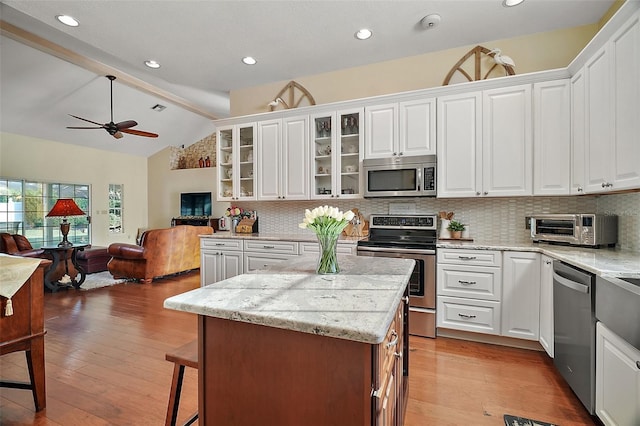 kitchen featuring lofted ceiling, appliances with stainless steel finishes, light hardwood / wood-style floors, and white cabinets