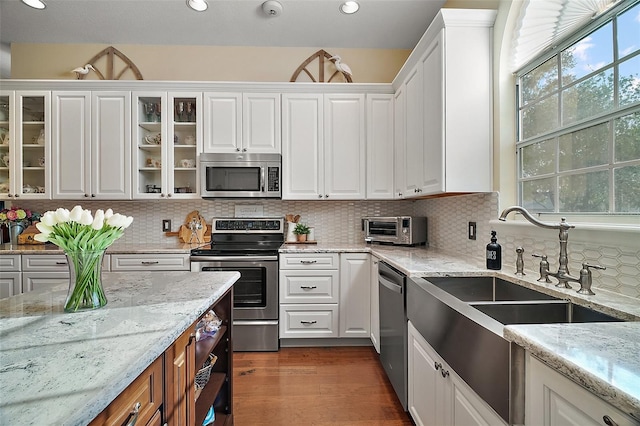 kitchen featuring sink, white cabinetry, light stone counters, appliances with stainless steel finishes, and backsplash