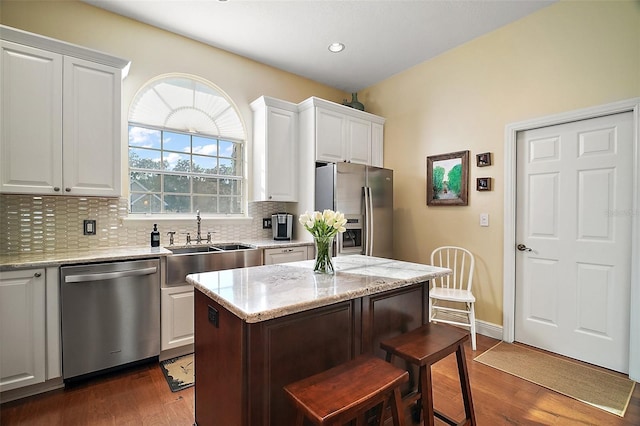 kitchen with light stone counters, appliances with stainless steel finishes, a kitchen island, and white cabinets