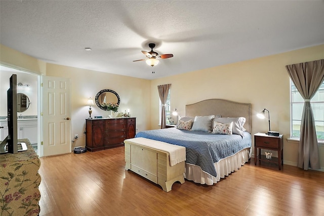 bedroom with ceiling fan, hardwood / wood-style flooring, and a textured ceiling