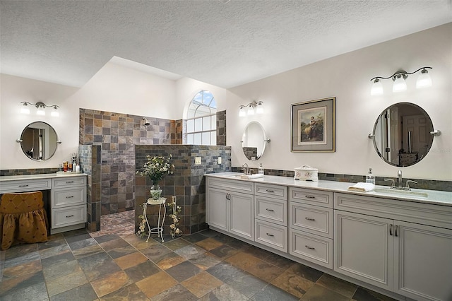 bathroom with tile walls, vanity, a textured ceiling, and walk in shower