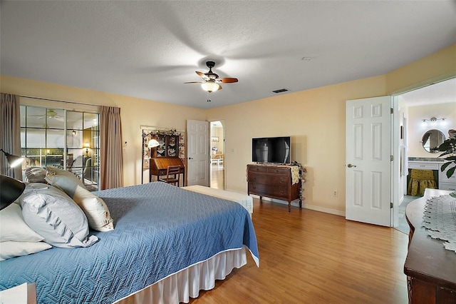 bedroom featuring ceiling fan, wood-type flooring, and a textured ceiling