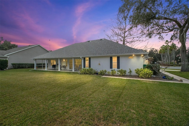 19215 Park Place Blvd, Eustis, FL 32736 - back of house at dusk featuring a patio area, a lawn, stucco siding, and roof with shingles
