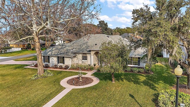 19215 Park Place Blvd, Eustis, FL 32736 - view of front facade featuring stucco siding, a front yard, and a shingled roof