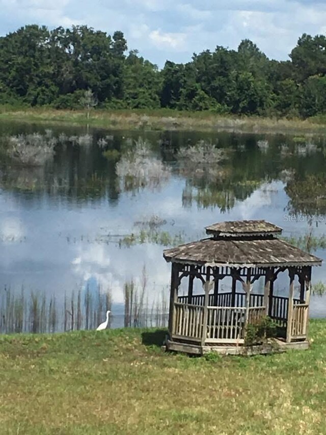 view of dock with a forest view, a water view, and a gazebo