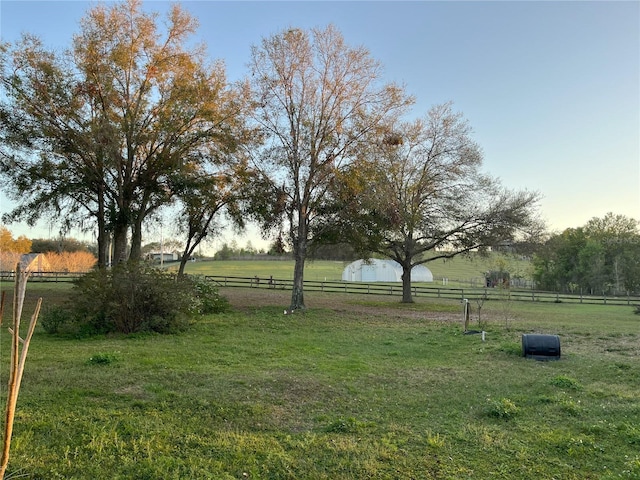 view of yard with fence and a rural view