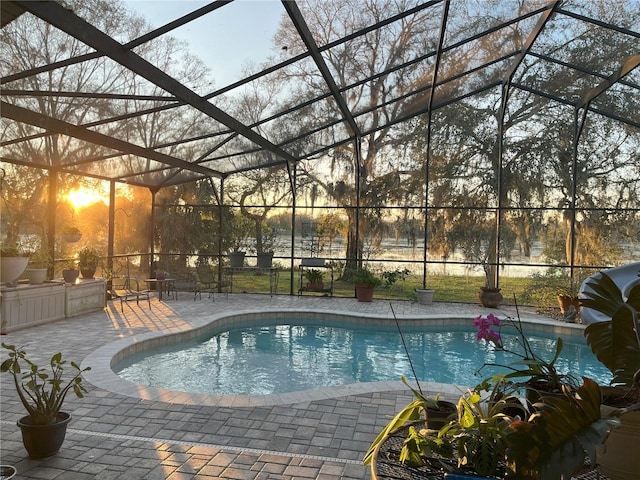 pool at dusk with a lanai, a patio area, and an outdoor pool