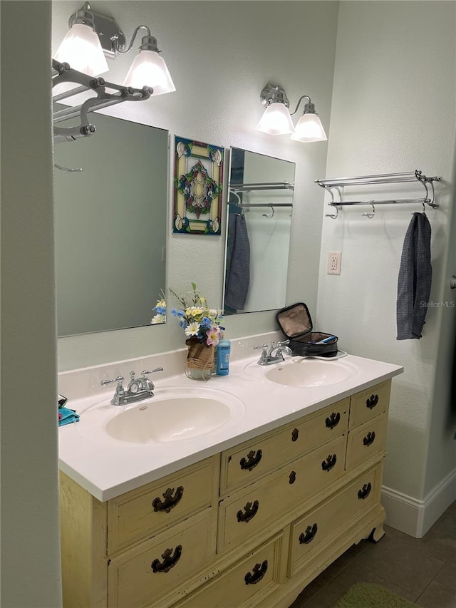 full bathroom featuring double vanity, baseboards, and a sink