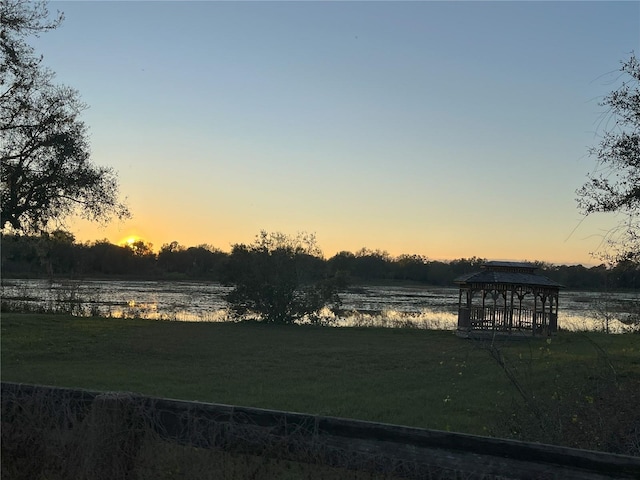 yard at dusk featuring a water view and a gazebo