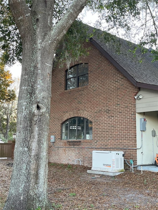 view of property exterior with brick siding and roof with shingles