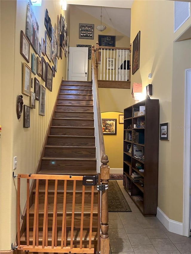 stairs featuring tile patterned flooring, baseboards, and vaulted ceiling