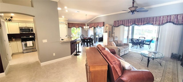 living room featuring lofted ceiling, light tile patterned floors, ceiling fan with notable chandelier, and ornamental molding