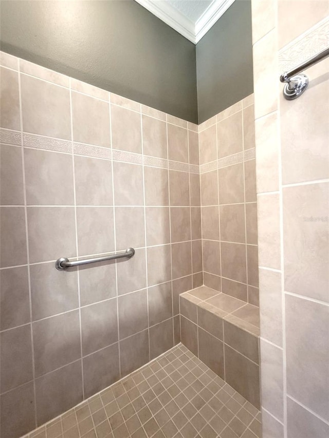 bathroom featuring ornamental molding and tiled shower