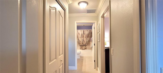 hall with light tile patterned floors, crown molding, and a textured ceiling