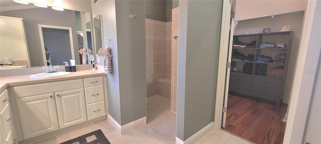 bathroom with tile patterned flooring, vanity, and tiled shower