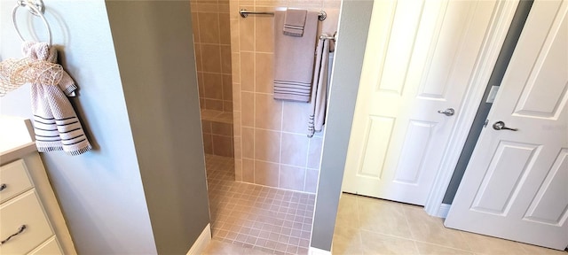 bathroom with tiled shower, vanity, and tile patterned flooring