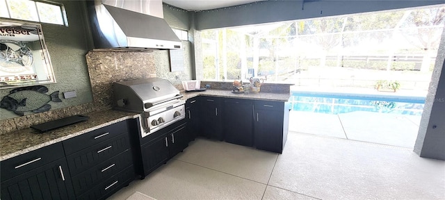 kitchen featuring light tile patterned floors, wall chimney exhaust hood, and stone countertops