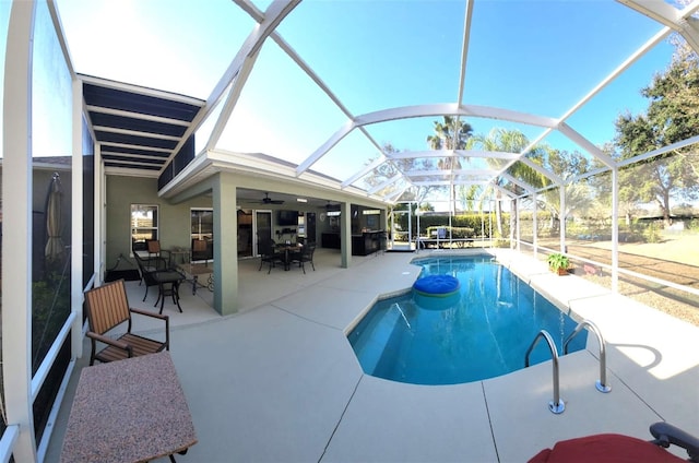 view of swimming pool with ceiling fan, a patio area, and glass enclosure