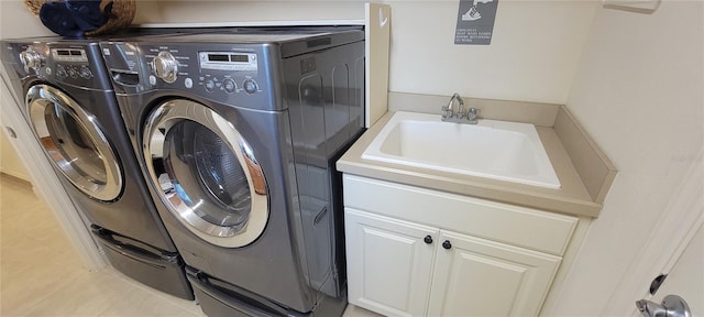 laundry area with sink, light tile patterned floors, washing machine and dryer, and cabinets