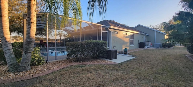 view of side of property with a lanai, central AC unit, and a lawn