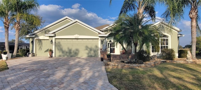 view of front facade featuring stucco siding, decorative driveway, an attached garage, a front yard, and concrete block siding