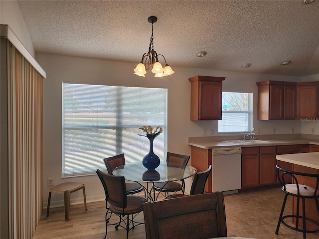 kitchen featuring sink, dishwasher, an inviting chandelier, hanging light fixtures, and a textured ceiling