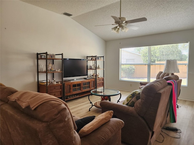 living room featuring ceiling fan, lofted ceiling, a textured ceiling, and light wood-type flooring