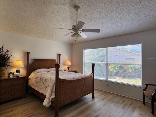 bedroom with ceiling fan, hardwood / wood-style flooring, and a textured ceiling