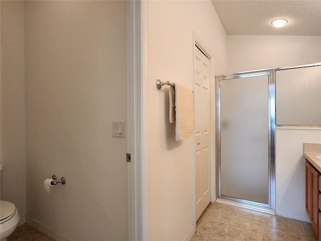 bathroom featuring vanity, toilet, a shower with shower door, and a textured ceiling