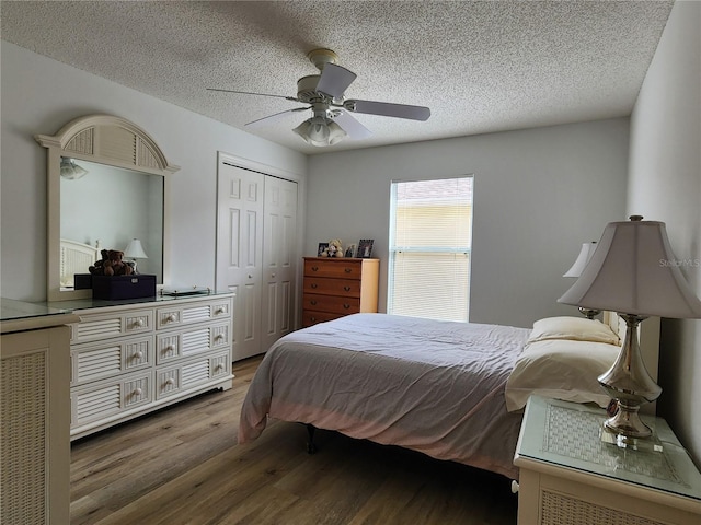 bedroom with ceiling fan, wood-type flooring, a closet, and a textured ceiling