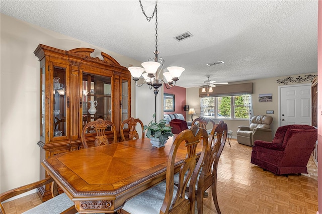 dining area with light parquet flooring, ceiling fan with notable chandelier, and a textured ceiling