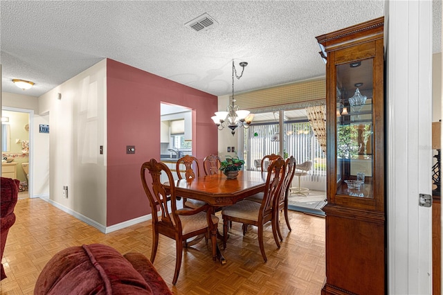 dining space with an inviting chandelier, a textured ceiling, and light parquet floors