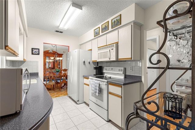 kitchen featuring white cabinetry, white appliances, a textured ceiling, and backsplash