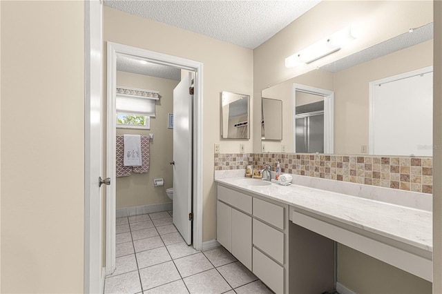 bathroom featuring tasteful backsplash, tile patterned flooring, vanity, toilet, and a textured ceiling